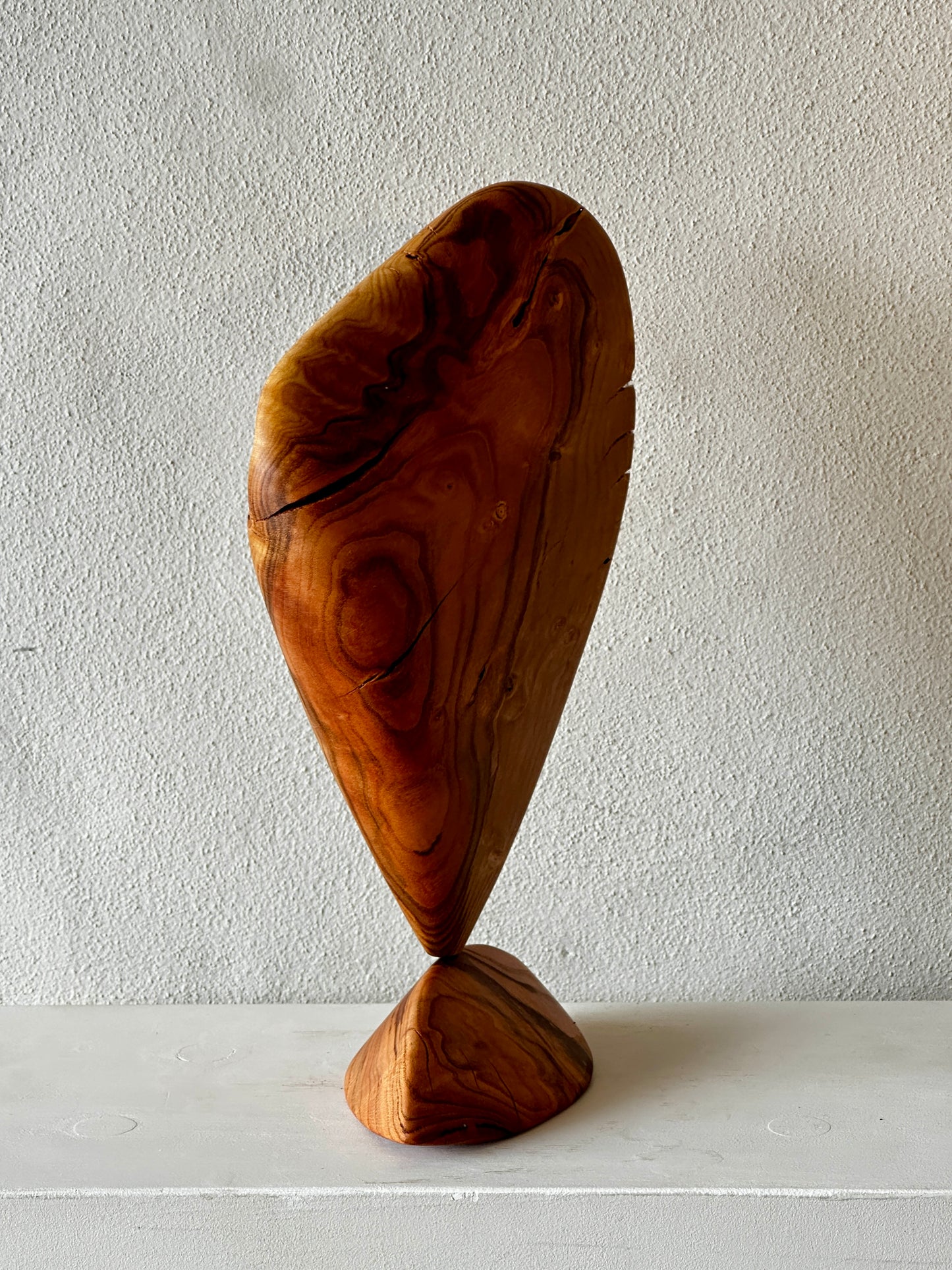 Wooden sculpture on a white surface with a plain background