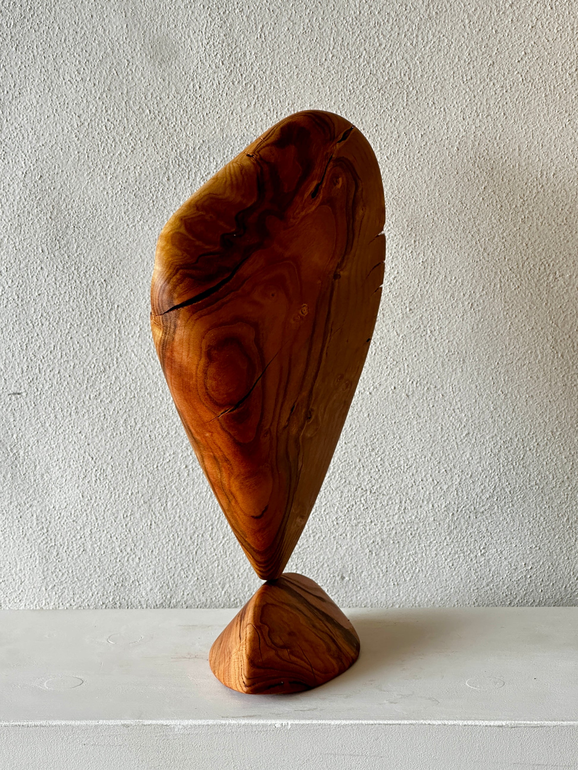 Wooden sculpture on a white surface with a plain background