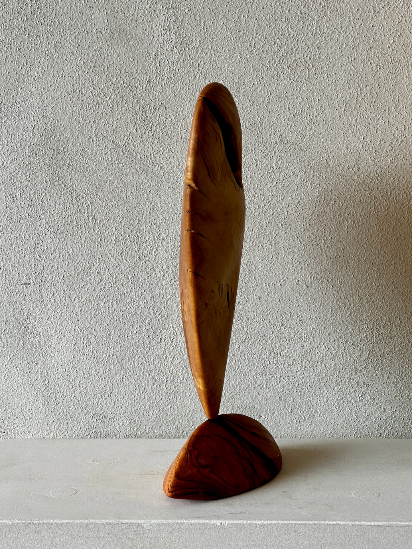 Wooden sculpture with a minimalist design on a plain background