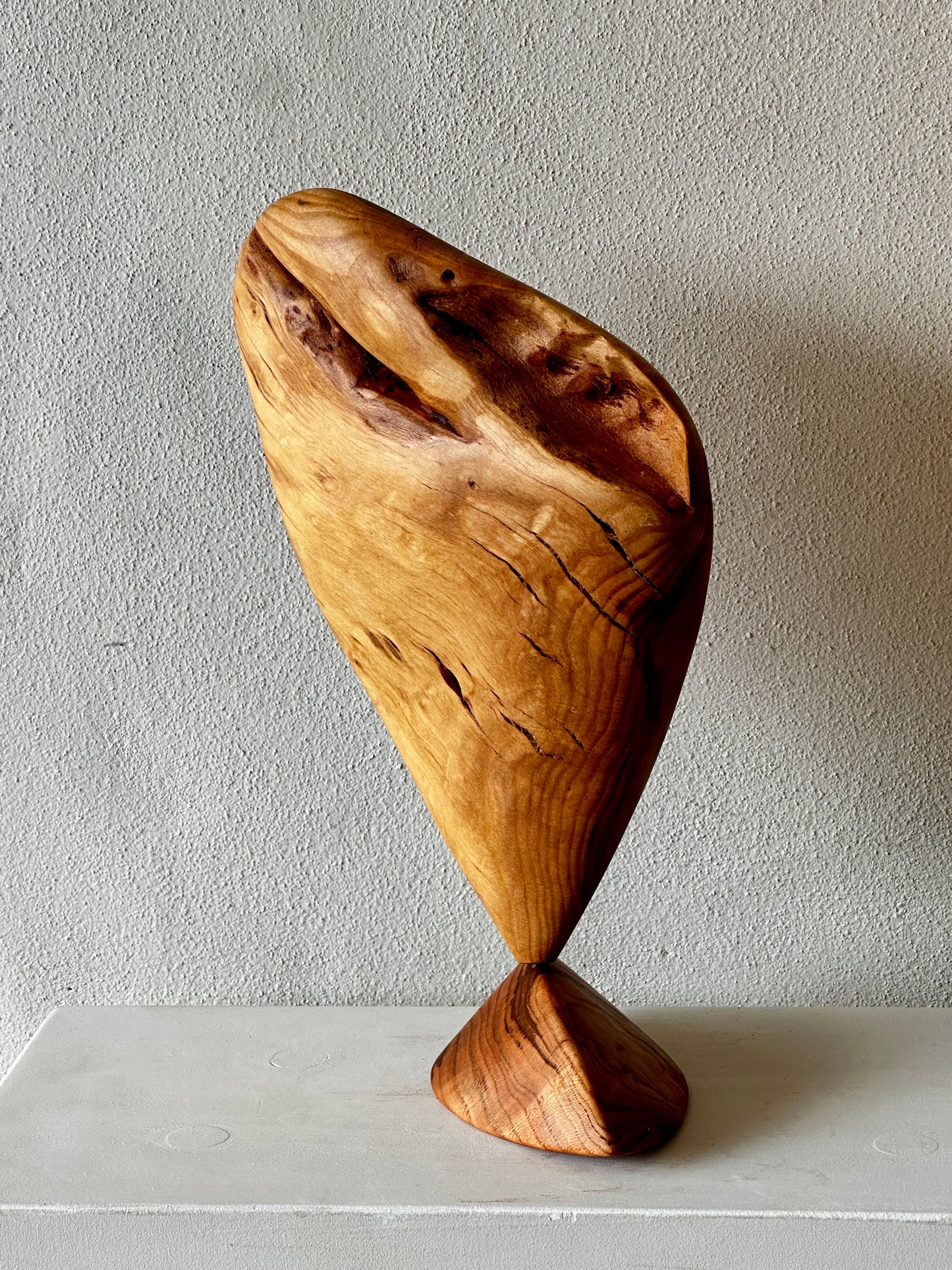 Wooden sculpture on a white surface with a plain background